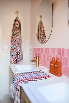 a bathroom with two sinks, mirrors and towels on the wall above them in different colors