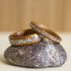 two wooden wedding rings sitting on top of a rock next to each other, with glitter in the middle