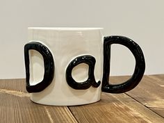 a black and white coffee mug with the word dad written on it's side