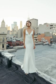 a woman standing on top of a roof wearing a white dress and looking off into the distance