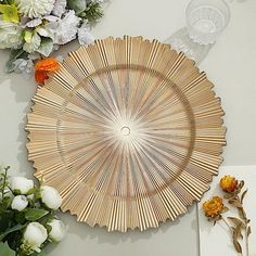 a wooden plate sitting on top of a table next to flowers