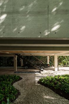 a car is parked under an overpass on the side of a building with trees