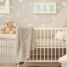 a teddy bear sitting in a crib next to a wall with flowers on it