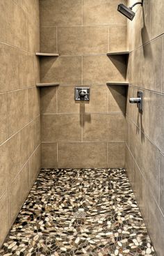 a walk in shower sitting next to a tiled wall and floor with shelves on each side