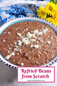 a bowl filled with refried beans and feta cheese next to some yellow flowers