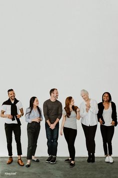 a group of people standing next to each other in front of a white wall and smiling