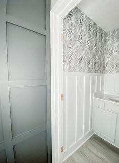 an empty bathroom with white cabinets and gray wallpaper