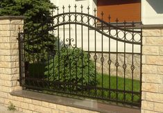 an iron gate is in front of a brick building with a green bush growing out of it