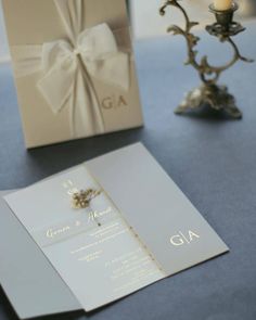 a wedding card with a bow on it next to a candle