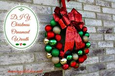 a christmas ornament wreath hanging on the side of a brick wall with a red bow