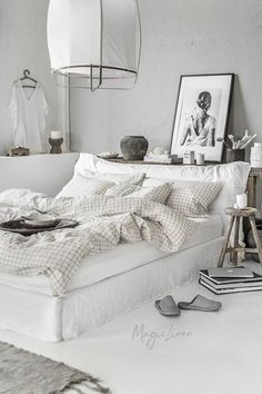 a white bed sitting in a bedroom next to a lamp and pictures on the wall