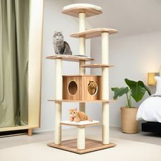 a cat tree with two cats sitting on top of it in a bedroom next to a bed