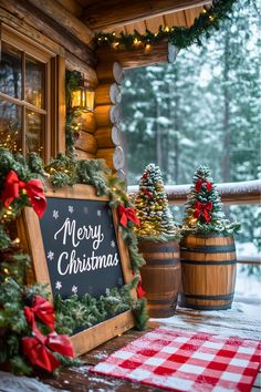 christmas decorations on the front porch of a log cabin with a merry sign and pine trees