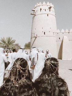 some people are standing in front of a white building and one is wearing a headdress