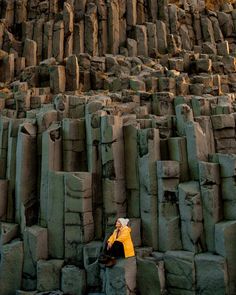 a man sitting on top of a pile of rocks next to a tall tower like structure