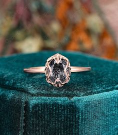 a diamond ring sitting on top of a green velvet covered cushioned surface with an intricate design