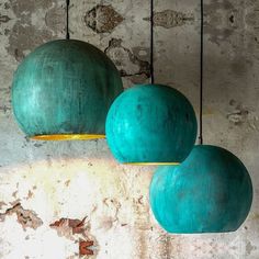 three green balls hanging from the ceiling in a room with concrete walls and peeling paint