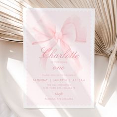 a pink birthday party card with a bow on the front, and text that reads charlotte is turning one