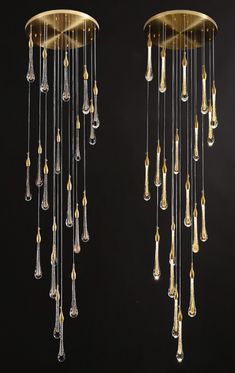 two chandeliers hanging from the ceiling with glass drops in gold and clear colors