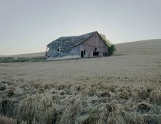 an old barn sitting in the middle of a field