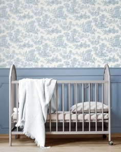 a baby crib in front of a blue wallpaper