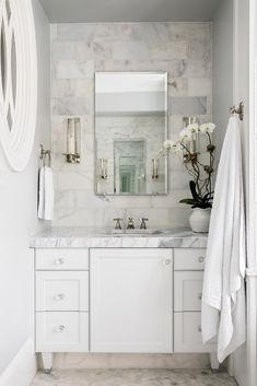 a bathroom with marble counter tops and white cabinets