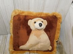 a stuffed animal sitting on top of a brown and white pillow with a teddy bear in the center