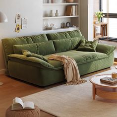 a green couch sitting on top of a hard wood floor next to a coffee table