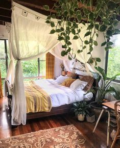 a bedroom with a canopy bed and plants hanging from the ceiling