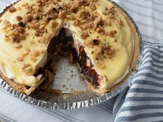 a pie with white frosting and walnuts on top sitting on a blue and white towel