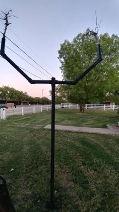 a metal pole in the middle of a grassy field next to a white fence and trees