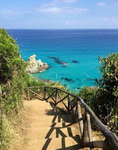 stairs leading down to the beach with blue water