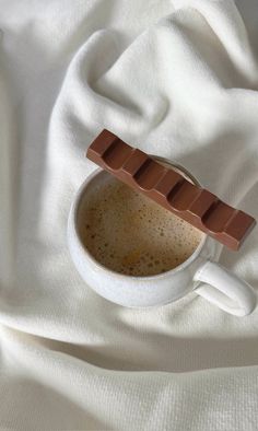 a cup of hot chocolate on top of a white cloth with an ice cream bar sticking out of it