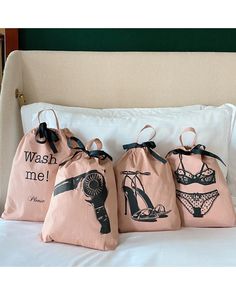 three bags with different designs on them sitting on a bed in front of a pillow