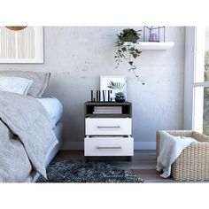 a white nightstand sitting next to a bed with a plant on top of it in front of a window