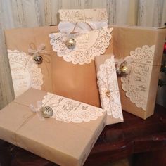 three brown boxes with white doily and bells on them sitting next to each other