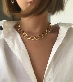 a woman wearing a white shirt with a gold chain necklace on her neck and chest