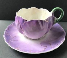 a purple tea cup and saucer on a black table