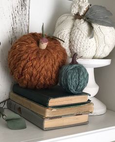 two knitted pumpkins sitting on top of books