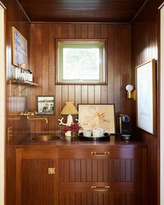 a room with wood paneling and a window on the wall above it is a sink