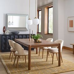 a dining room table and chairs in front of a large window with an area rug on the floor