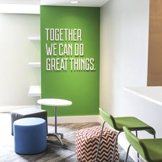 an office with green walls and white letters on the wall, two chairs and a round table