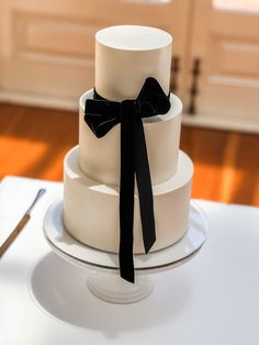 a three tiered white cake with black ribbon