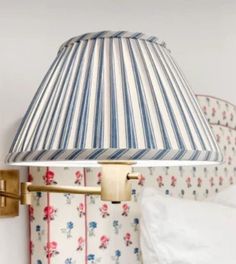 a lamp that is on the side of a wall next to a bed and pillows