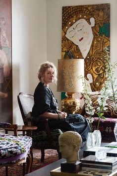 a woman sitting in a chair next to a lamp