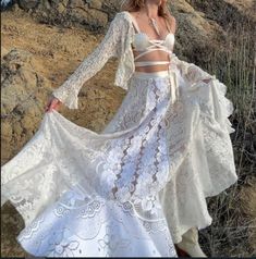 a woman in a white dress standing on top of a hill