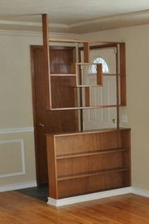 an empty living room with wood floors and white trim on the walls, including a bookcase