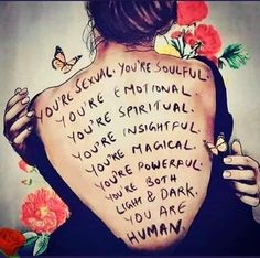 the back of a woman's body with words written on it and flowers around her