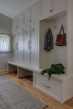 a room with white cupboards and wooden flooring next to a rug on top of a hard wood floor