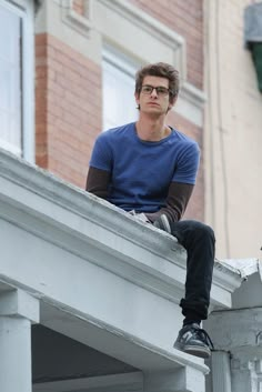 a young man sitting on top of a building